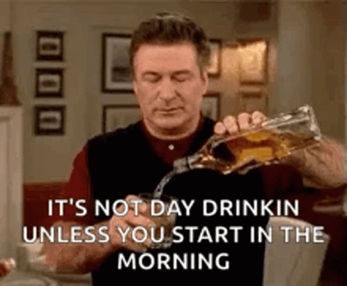 Alec Baldwin's character on 30 Rock takes a sip of alcohol with a joyous expression on his face, signifying a desire to drink or a celebration.