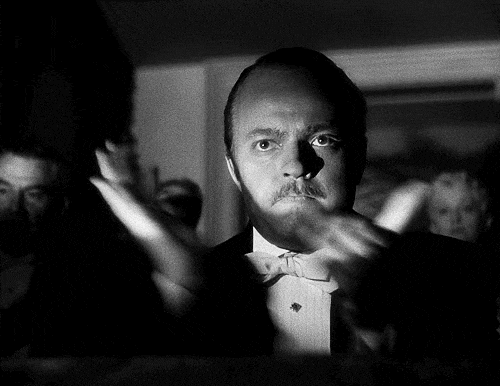Orson Welles sarcastically clapping his hands together to mock incompetence or failure.